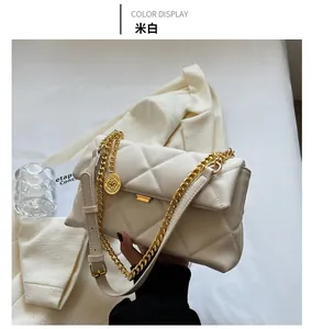 Detail of cream white quilted handbag featuring gold chunky chain and metallic logo charm