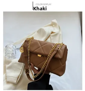 Detail of khaki quilted leather shoulder bag with gold chain strap held by a person