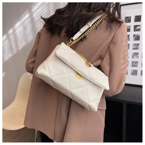 Close-up of white quilted shoulder bag with gold chunky chain strap and round pendant