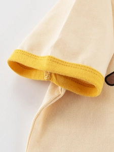 Gros plan des poignets côtelés jaunes sur un t-shirt beige en coton pour filles