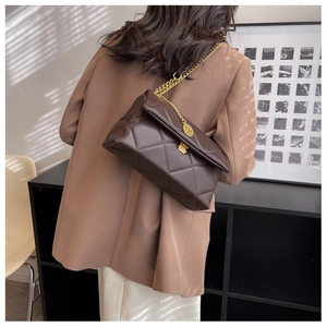 Close-up of quilted brown shoulder bag with golden chain and metallic buckle detail