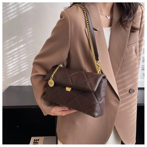 Detail of dark brown quilted crossbody bag with gold chain and matte leather finish