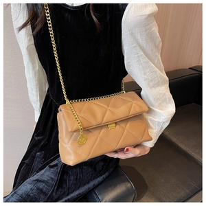 Close-up of quilted rhombic chain bag with gold hardware worn by a model in a velvet dress