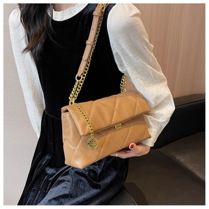 Detail of tan quilted faux leather shoulder bag with gold chain strap and metal charm