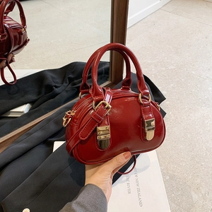 Glossy red leather bowling bag with gold hardware and dual handles for women