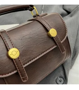 Detail of vintage brown leather handbag featuring 3D gold metal buckles and fine stitching