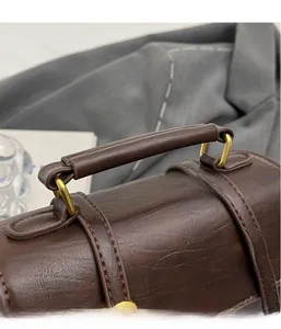 Detail of dark brown vintage handbag featuring reinforced top handle and gold hardware