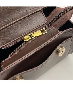 Detailed macro view of dark brown textured leather bag with gold metal zipper puller