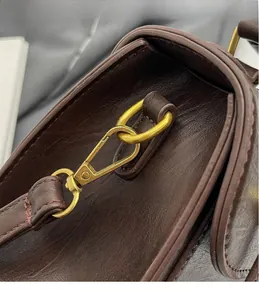 Close-up of vintage brown leather bag featuring durable bronze-tone metal swivel hooks