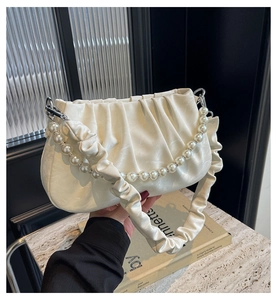 Detailansicht der cremeweißen Cloud-Bag mit Perlengriff und geraffter PU-Lederstruktur