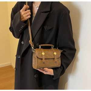 Close-up of brown vintage crossbody bag with gold buckle and matte leather texture