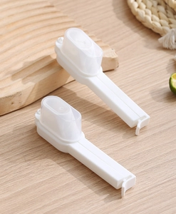 Dual white plastic sealing clips with pouring spouts on a natural wooden background