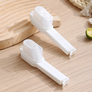 Food bag sealing clip with pouring spout made of white plastic on a wooden tabletop