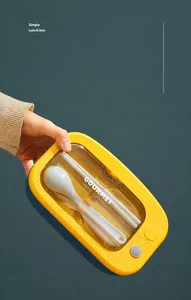 Detail of yellow and blue lunch box lid with built-in cutlery storage and gray utensils