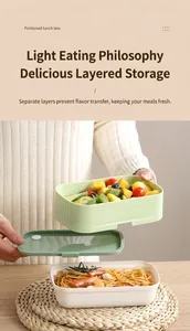 Detail of a green and white stackable lunchbox with separate layers for pasta and fruit