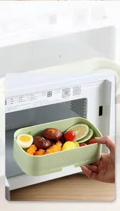Close-up of a stackable green bento box with fresh food being heated in a microwave