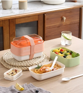 Close-up of a layered bento box with matching elastic strap and plastic utensils