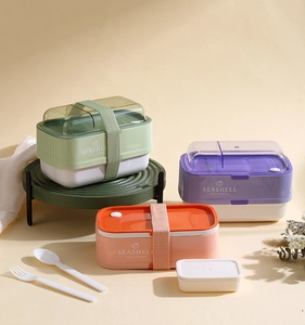 Detailed view of stackable bento boxes in pastel colors with elastic bands and utensils