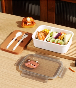 Detalle de fiambrera bento con compartimentos, bandeja de cubiertos y tapa de oso