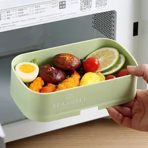 Pale green rectangular stackable bento lunch box with food inside a microwave oven