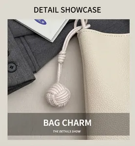 Close-up of beige lychee leather square bag with handcrafted woven ball charm detail