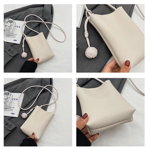 Detail of creamy white litchi pattern mini crossbody bag with unique knot ball strap