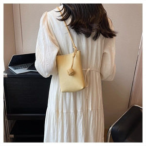 Detail view of a yellow mini leather crossbody bag with braided knot design on model
