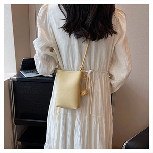 Rear view of model wearing a light yellow litchi leather mini phone crossbody bag