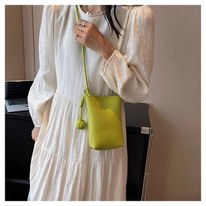 Macro detail of fluorescent green leather mini shoulder bag with sphere knot strap