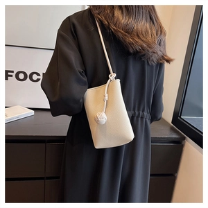 Detail of a cream faux leather crossbody phone bag with knot decorative strap on model