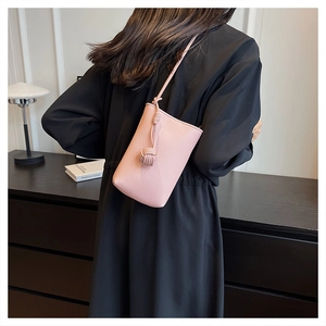 Detail of light pink pebble leather phone bag featuring a stylish knotted tassel accent