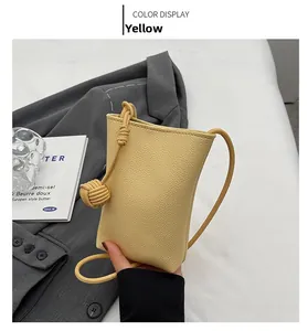 Detailed close-up of yellow pebble grain leather phone bag with thick knotted shoulder strap