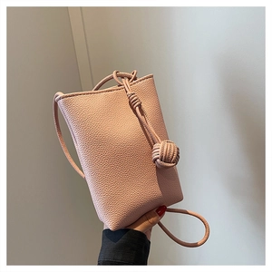 Detailed view of pink pebble-textured leather on a mini vertical crossbody bag