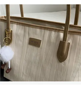 Detailed view of the wavy embossed texture and cute pendant on an off-white tote bag