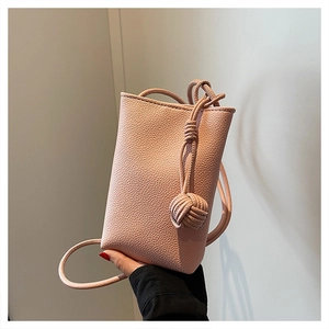 Close-up of pink litchi grain leather mini crossbody bag with knot shoulder strap detail