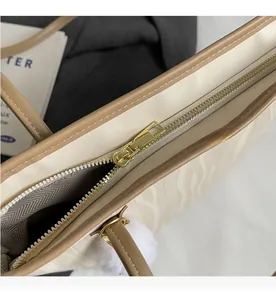 Detailed macro view of the smooth gold metal zipper and white faux leather on the tote bag