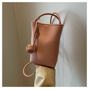 Close-up of pink litchi grain leather mini bag with woven knot detail and slim strap