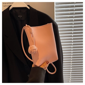 Detail of pink pebbled leather mini crossbody bag with stylish knotted shoulder strap