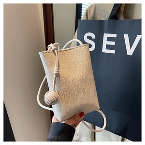 Close-up of cream square mini bag featuring litchi grain texture and knotted strap
