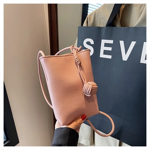 Close-up of pink litchi grain leather crossbody bag with a knotted strap design
