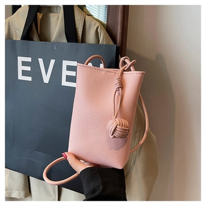 Detail of pink pebbled leather mini crossbody bag with decorative knot and slim strap