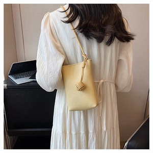 Close-up of cream textured leather mini shoulder bag with knot detail on white dress