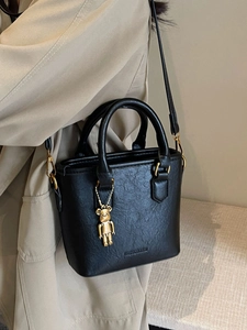 Borsa a mano retrò nera con dettagli dorati e ciondolo a orso su modella