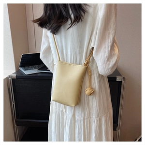 Close-up of beige litchi grain leather mini bag with decorative woven charm detailing