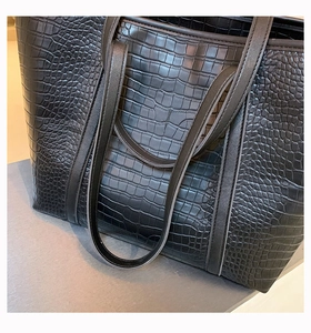 Close-up of black tote bag featuring luxury crocodile pattern embossing and fine texture