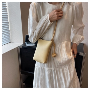 Detail of light yellow vertical crossbody phone bag with premium litchi leather texture
