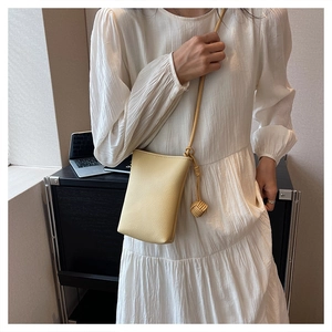 Close-up of bright yellow mini leather shoulder bag with decorative knot ball strap detail