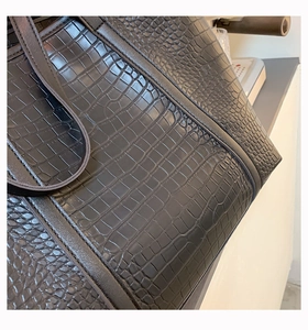 Close-up of black crocodile pattern leather texture and neat stitching on tote bag