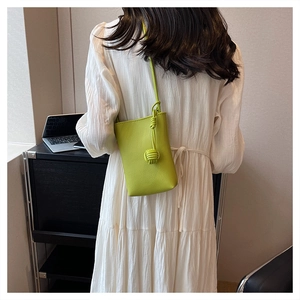 Mini lime green crossbody bag with textured leather and knot detail on white dress