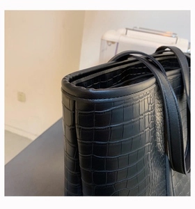Close-up of black crocodile embossed tote bag showing refined texture and durable strap